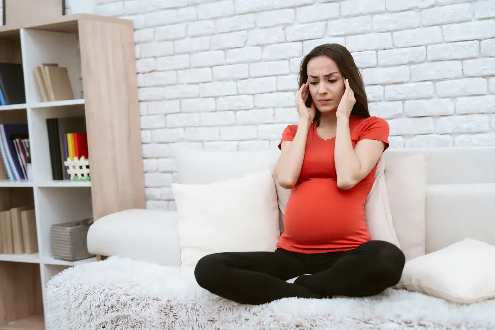 High-risk pregnancy: expecting mother with a headache resting on a sofa