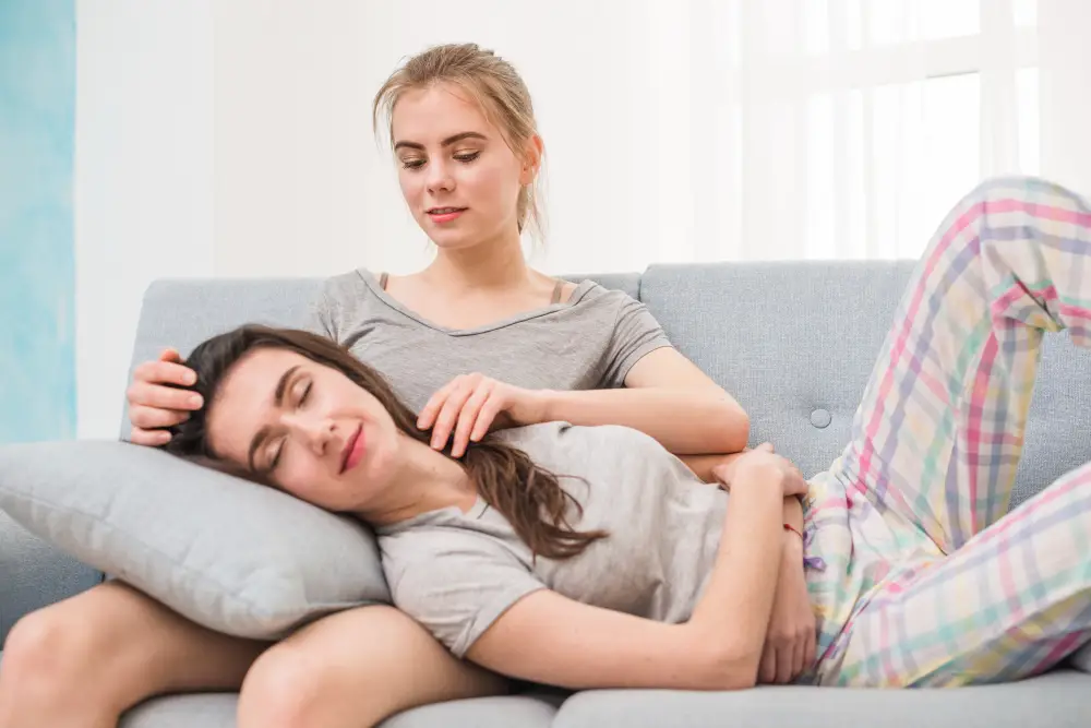 Woman with lower abdominal pain from an ovarian cyst, comforted on a sofa
